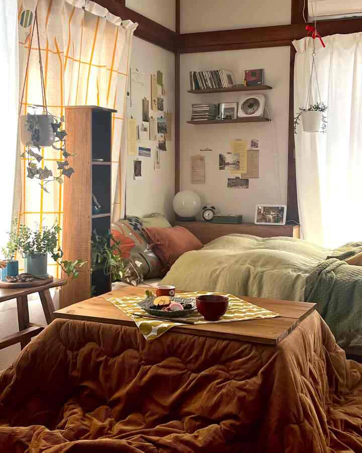 Natural tone cozy single household bedroom featuring a kotatsu table and a green bed with wooden elements