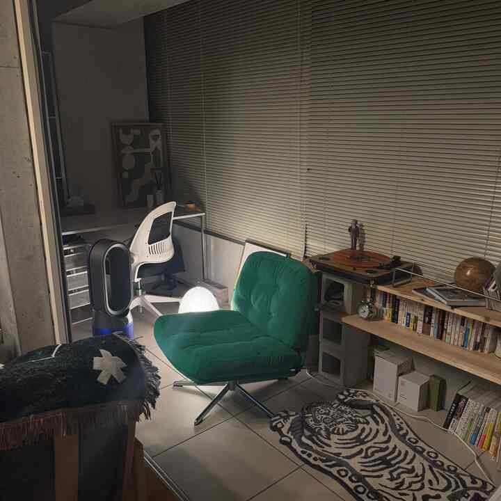 Nighttime natural modern living room with green armchair and bookshelf arranged in a cozy setting