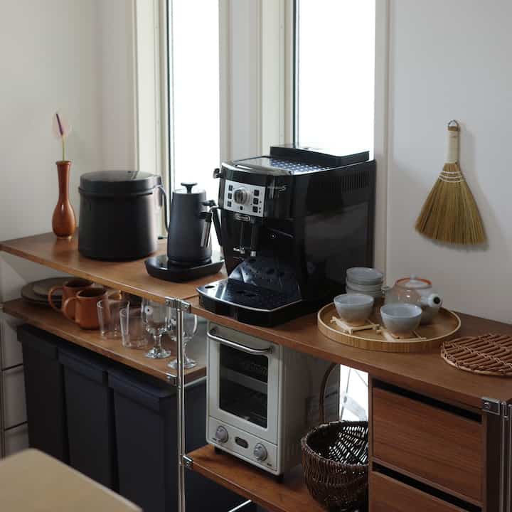 Natural brown-toned kitchen featuring Muji shelving, coffee machine, and neatly arranged teacups creating a cozy atmosphere