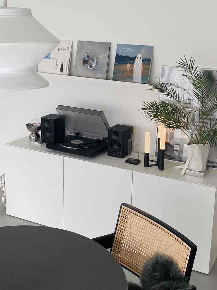 Modern living room with white walls and shelves featuring a turntable and records as a music listening space