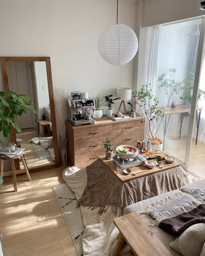 ナチュラルな木目調と植物が配置されたリビング、暖かい雰囲気のこたつと快適なベンチがある印象的な空間