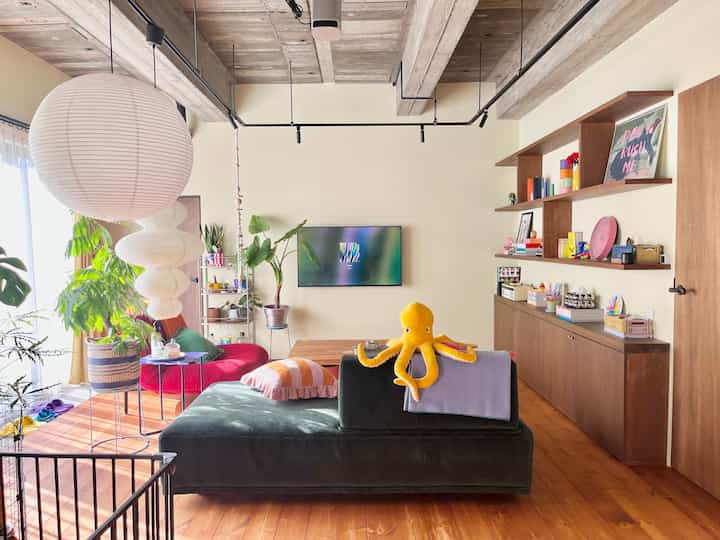 Bright and warm Mid-Century Modern living room with white walls, wood-tone floors, colorful sofa, and playful accessories