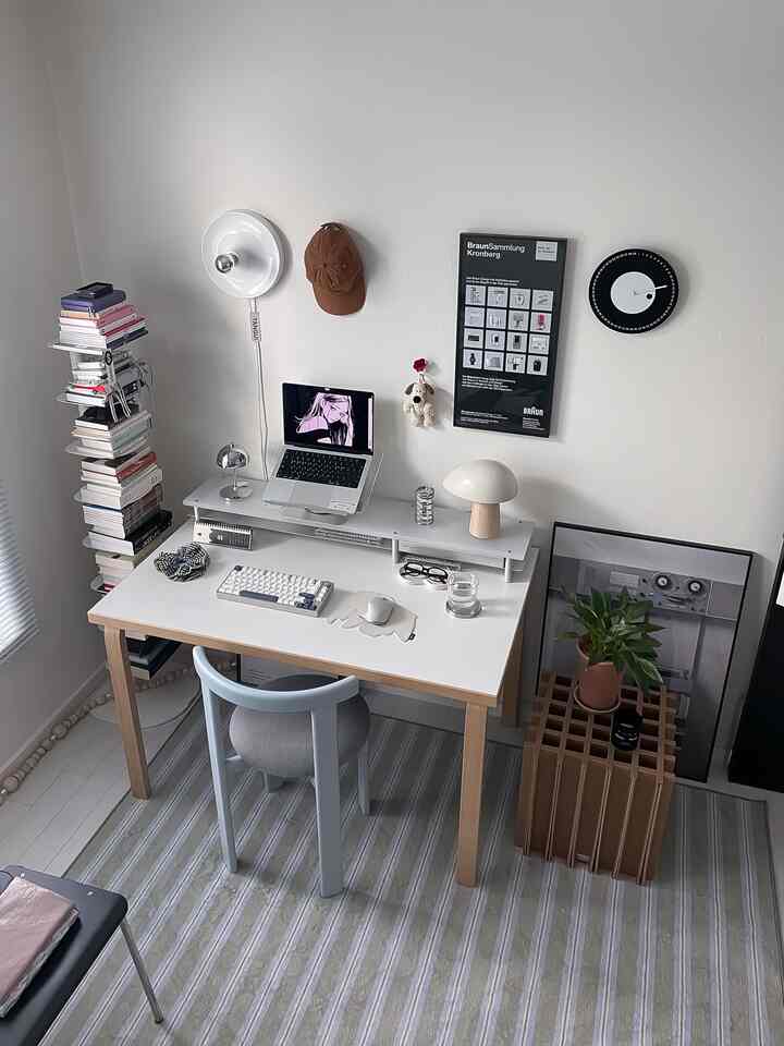 白とナチュラルカラーのコンパクトなホームオフィス、すっきりとしたデスクとチェア、本棚、植物が配置されたミニマルで雰囲気のあるインテリア