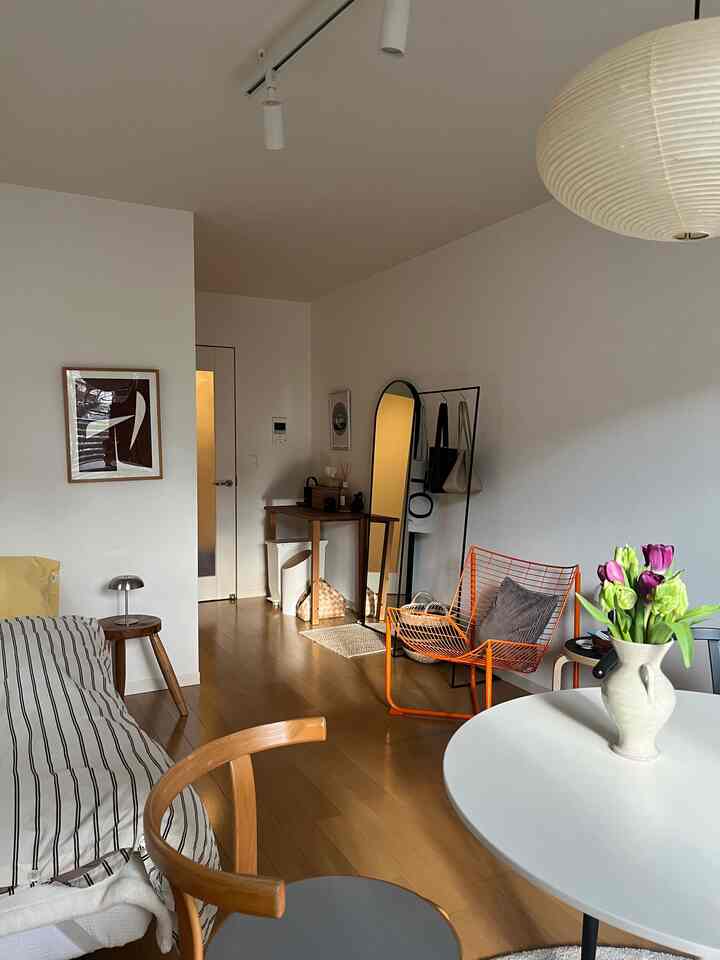 ライトブラウンのウッドフロアと白い壁のリビング、ナチュラルな家具とアールデコ調のミニマルな雰囲気のインテリア