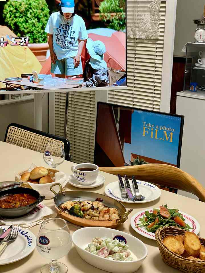ホワイトと木目調が調和したダイニングルーム、テーブルには様々な食器や料理が並び、温かみのある雰囲気のインテリア