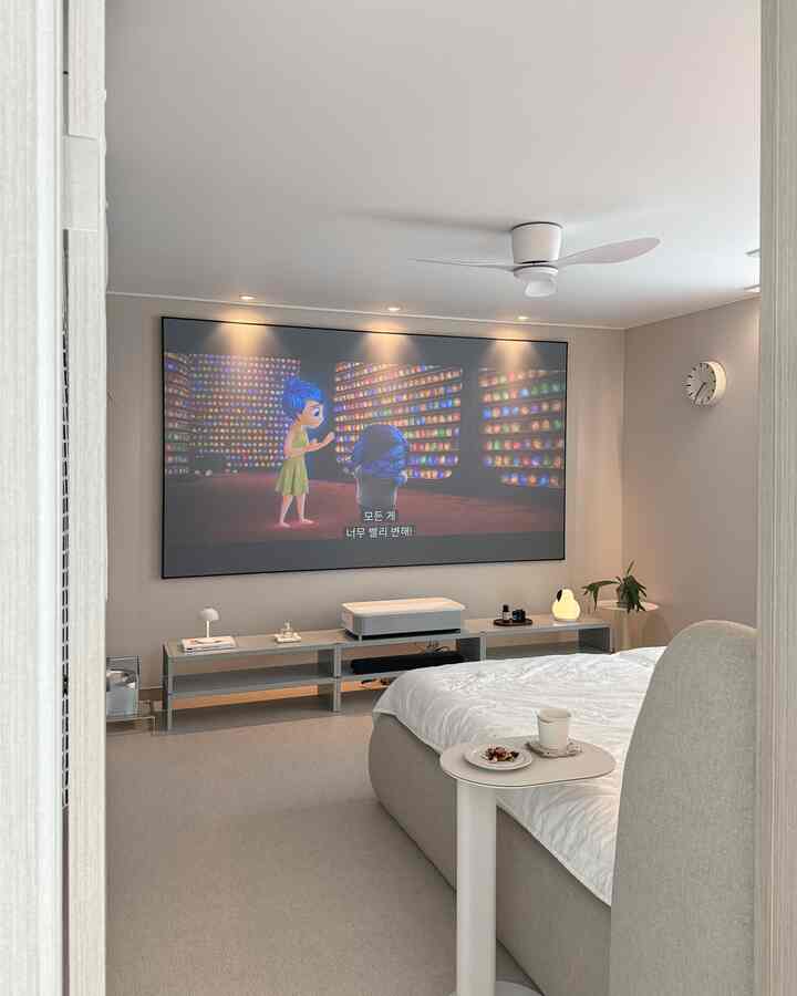 Beige and gray toned bedroom featuring ultra short throw projector and large projector screen with simple modern layout for home cinema