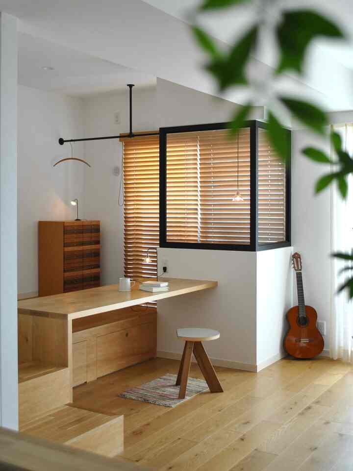Bright natural tone minimal home office featuring wooden desk, stool, and wood blinds in a clean workspace