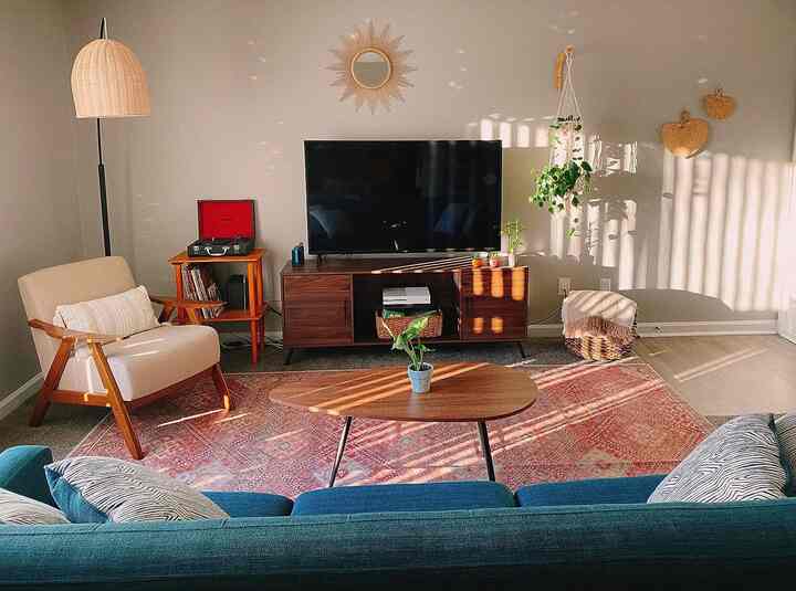 Warm red and brown toned mid-century modern living room featuring a blue sofa and wooden coffee table in a cozy setting
