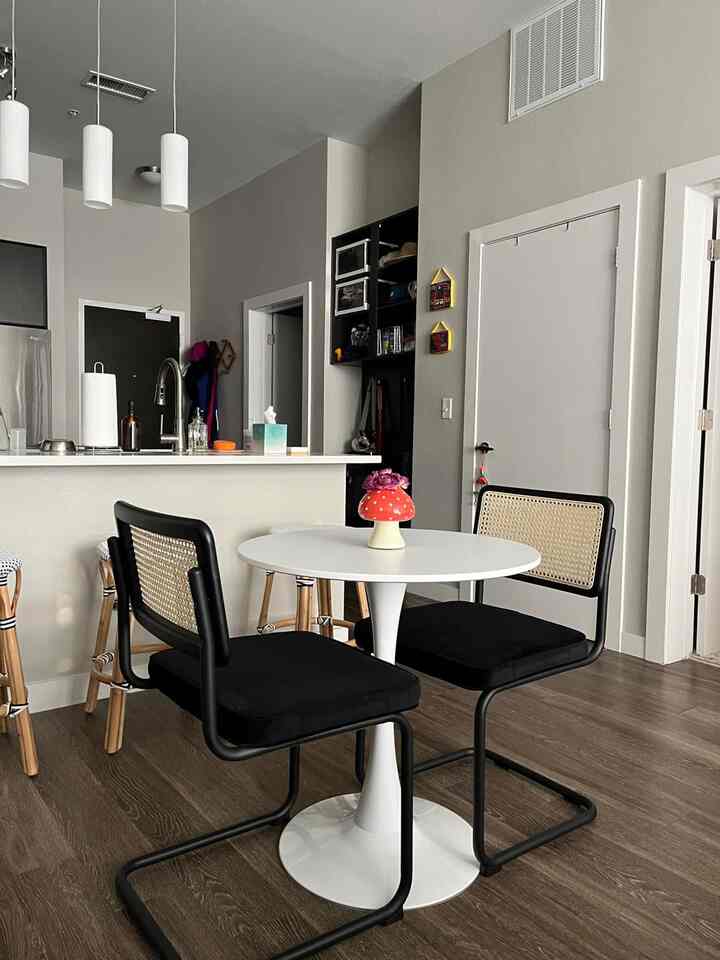 A modern black and white dining room featuring a sleek white table and black rattan-backed chairs with a clean, minimalist atmosphere
