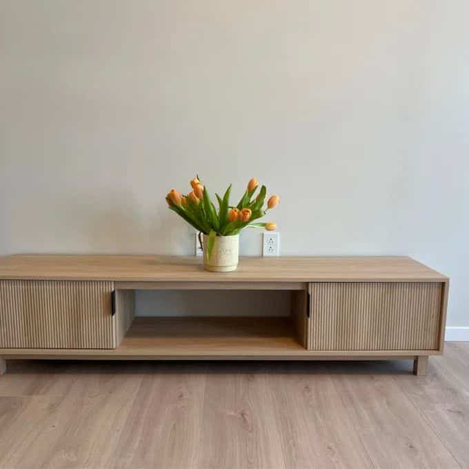 Wood tone natural color living room, simple design TV stand with vase featuring a clean and minimalist space