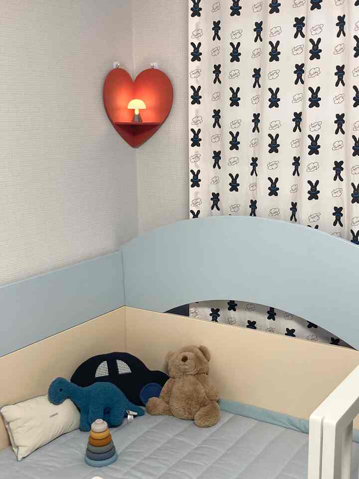 パステルブルーとベージュの幼児用寝室、ハート型の壁棚とぬいぐるみが配置された雰囲気のあるインテリア