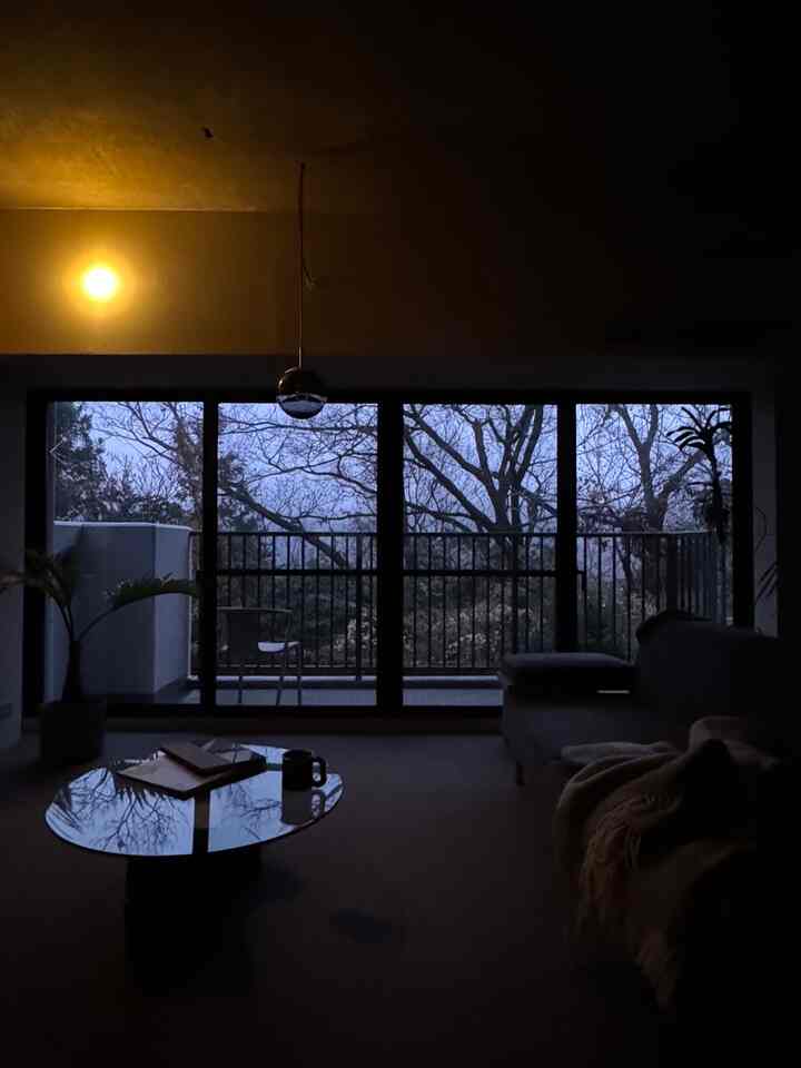 薄暗い照明と紫色の夕暮れが見えるバルコニーを備えたモダンなリビングルーム