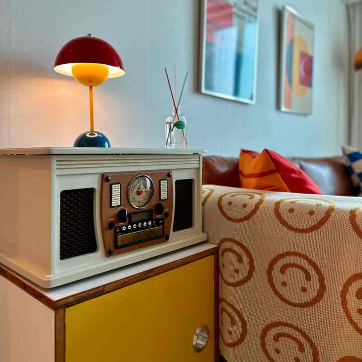 Mid-Century Modern living room with vivid yellow and red color accents, featuring sofa, lighting, and diffuser in a cozy setting