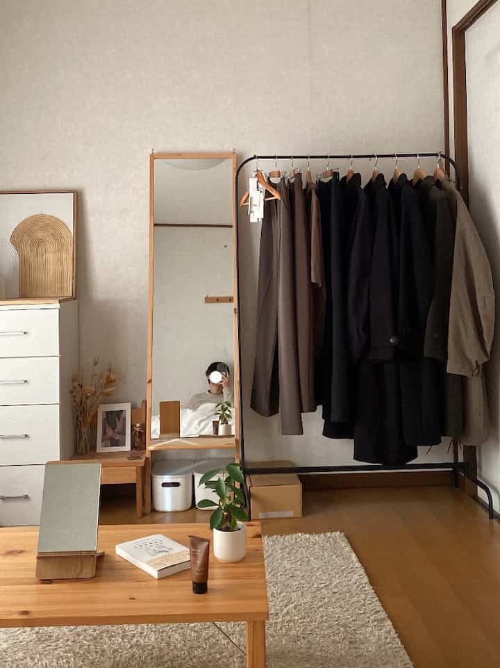 Natural color and wood tone living room featuring a coat rack and low table in a simple, cozy space