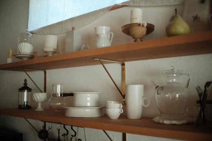 ナチュラルな木目調の棚に白いキッチン用品とキャンドルが置かれた雰囲気のあるキッチンスペース