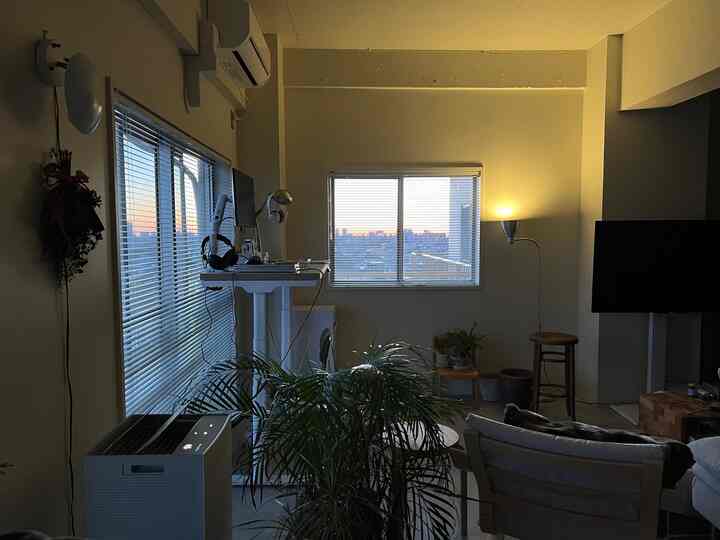 白と緑のトーンのリビング、モダンなスツールとスタンディングデスクが配置されたシンプルな印象的な空間