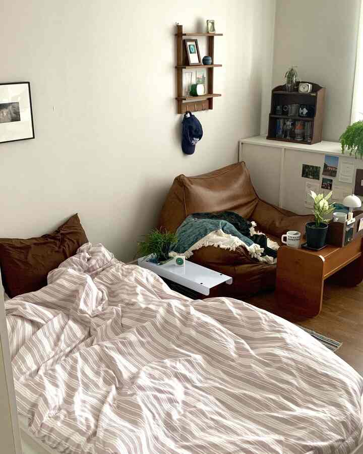 A natural-toned bedroom featuring a brown bean bag and striped bedding, creating a cozy atmosphere.
