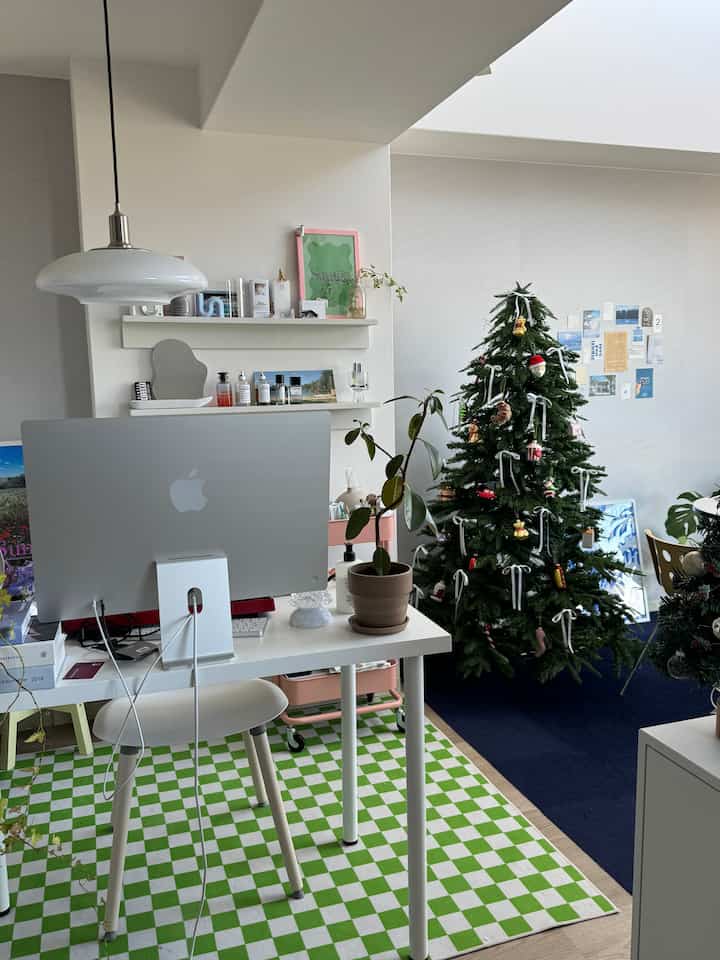 White toned studio apartment home office featuring a decorated Christmas tree and plants in a clean interior