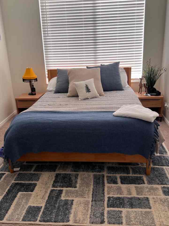 Beige-toned bedroom with blue bedding, wood tone bed frame and nightstands creating a cozy atmosphere