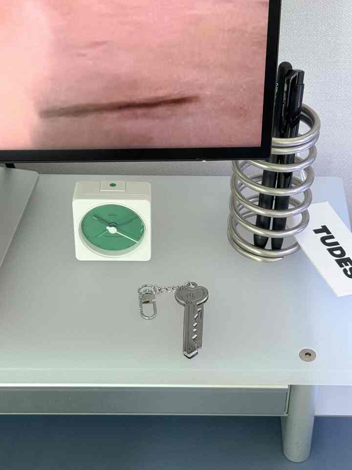 Gray-toned home office desk featuring a Starbucks analog clock, silver pen holder, and keychain, creating a neat workspace