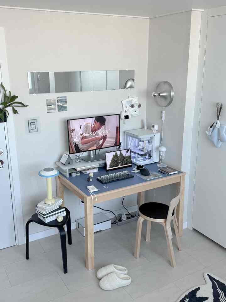 Natural modern home office space in white and blue tones featuring a desk with monitor stand and desk mat, arranged neatly.