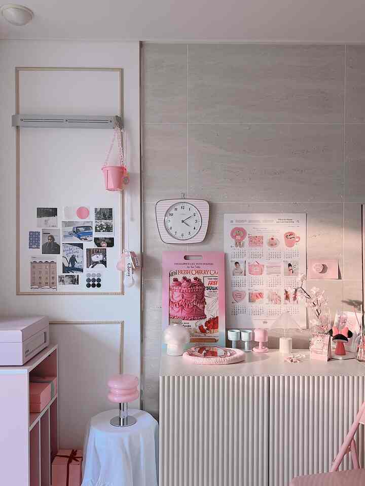 Pink-toned living room space featuring a pink chair, posters, and glass vase with charming decor elements