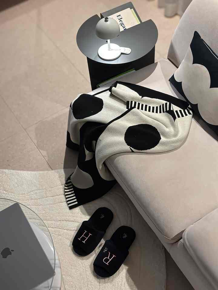 ホワイトとブラックのトーンの1人用リビング、シンプルなソファとサイドテーブル上のテーブルランプがあるミニマルな空間