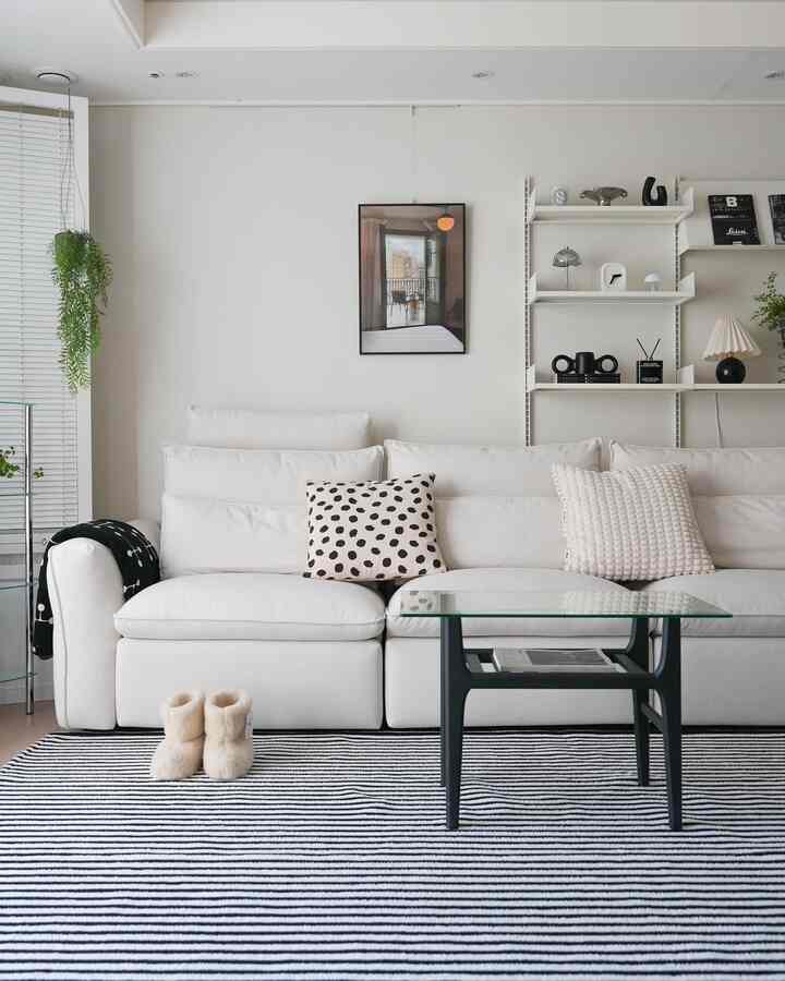 Monotone black and white living room featuring striped rug, sofa, clean shelves, and wall art with modern atmosphere