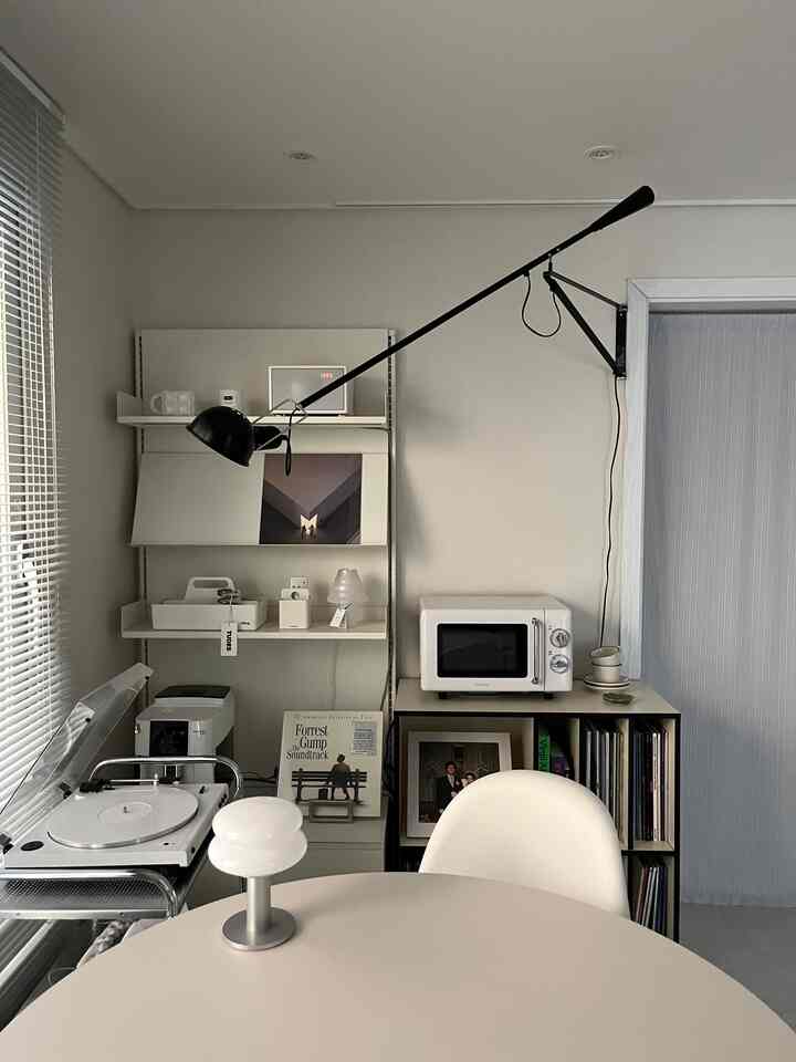 Monotone-toned living and dining space featuring a Pantone chair and large pendant light with a simple, minimalistic interior