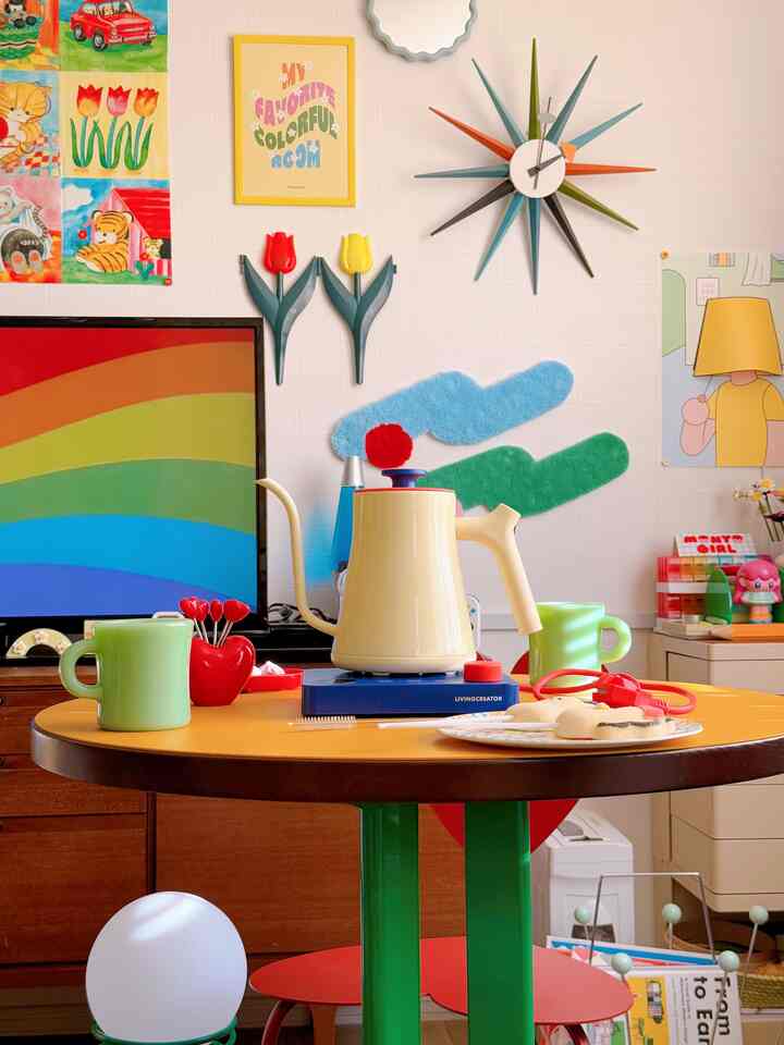 カラフルな壁と電気ケトル、円形のダイニングテーブルが配置されたレトロでミッドセンチュリーモダンなインテリア