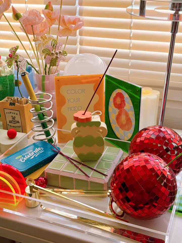 Colorful space featuring pastel green tile tray, red disco balls, and decorative objects with warm light from blinds