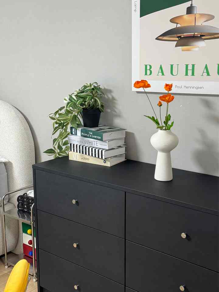 グレーの壁とマットブラックのチェストが置かれた寝室、植物と花瓶で飾られたナチュラルな雰囲気のインテリア