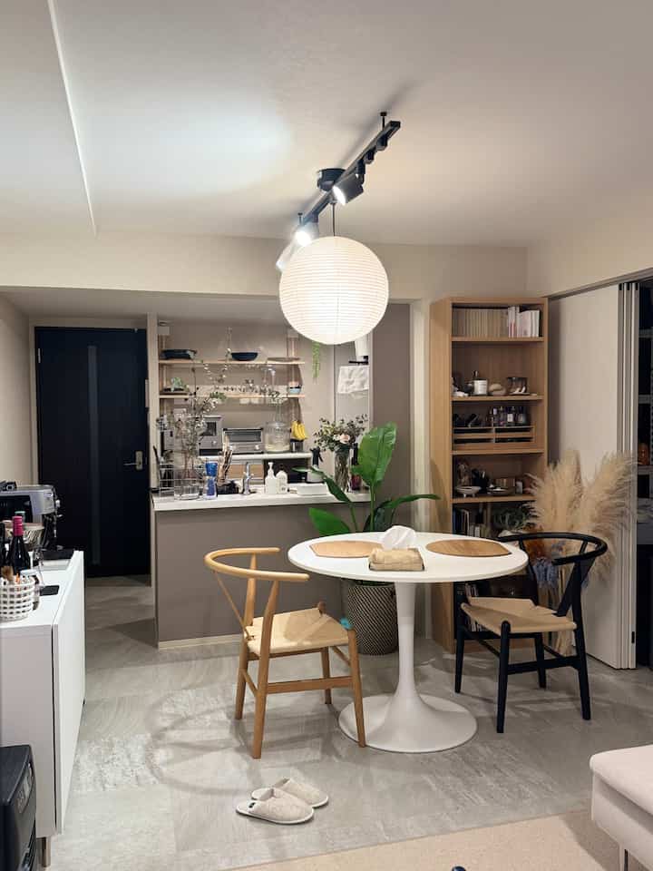 白と木目調の二人用ダイニングルーム、ミッドセンチュリーモダンの椅子とペンダントライトが配置された雰囲気のある北欧リビング