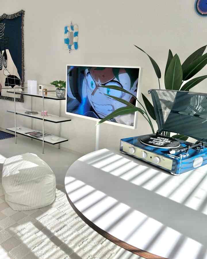 明るい白を基調としたリビング、丸テーブルとレトロなレコードプレーヤー、ビーズクッションと植物が配された雰囲気のある空間