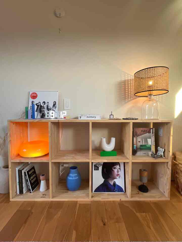 ナチュラルな木目調の本棚がある落ち着いたリビング、テーブルランプとさまざまな装飾で温かみのある雰囲気