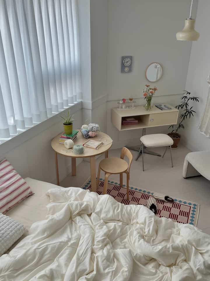 白と木目調のワンルーム寝室、ヴィンテージラグとシンプルな木製家具が温かみのある雰囲気のインテリア