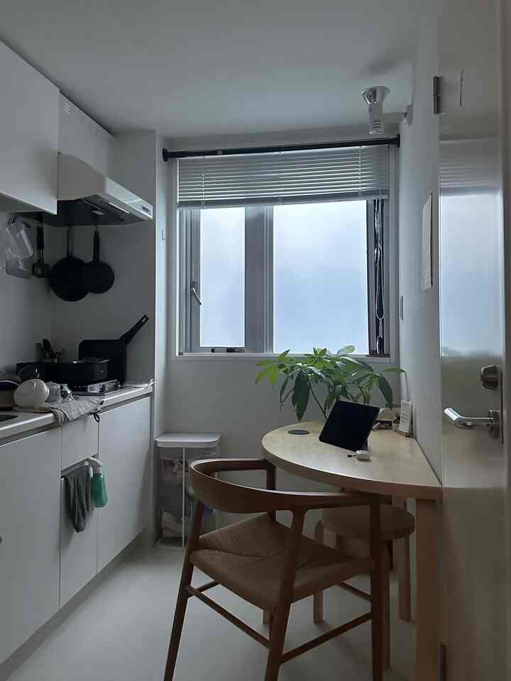 ホワイトとナチュラルウッドの色調が調和した1Kキッチン、コンパクトな空間にブラインドが配置された雰囲気のあるインテリア