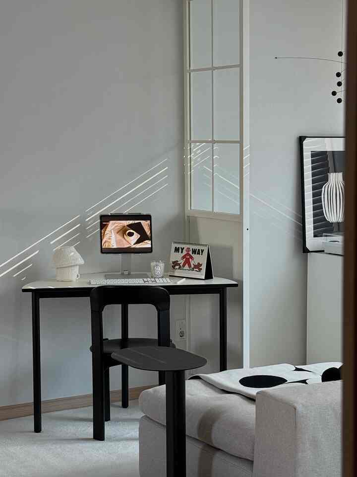Modern home office in white and black tones featuring a desk and chair in a calm workspace
