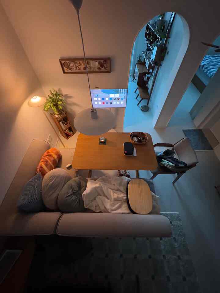 ベージュとブラウンの色調のリビング、ペンダントライトとソファ、木製のダイニングテーブルが配置された雰囲気のあるインテリア