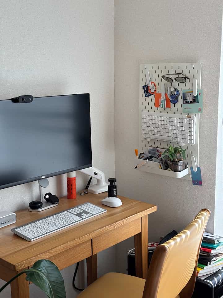 Natural wood tone desk with monitor stand and hanging wall organizer in a single household home office space