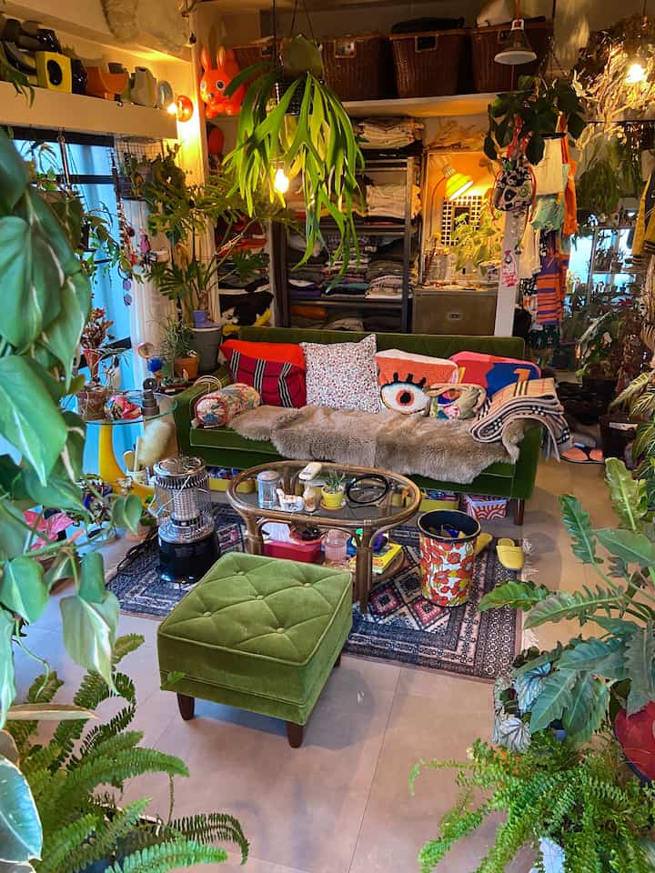 緑とナチュラルトーンのリビング、ミッドセンチュリーヴィンテージのソファとクッションが配置された雰囲気のあるインテリア