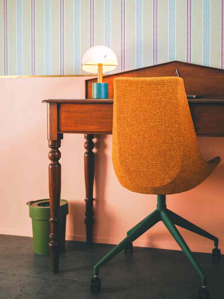 Wood tone and orange colored home office space featuring a wooden desk and an orange office chair with a cozy atmosphere