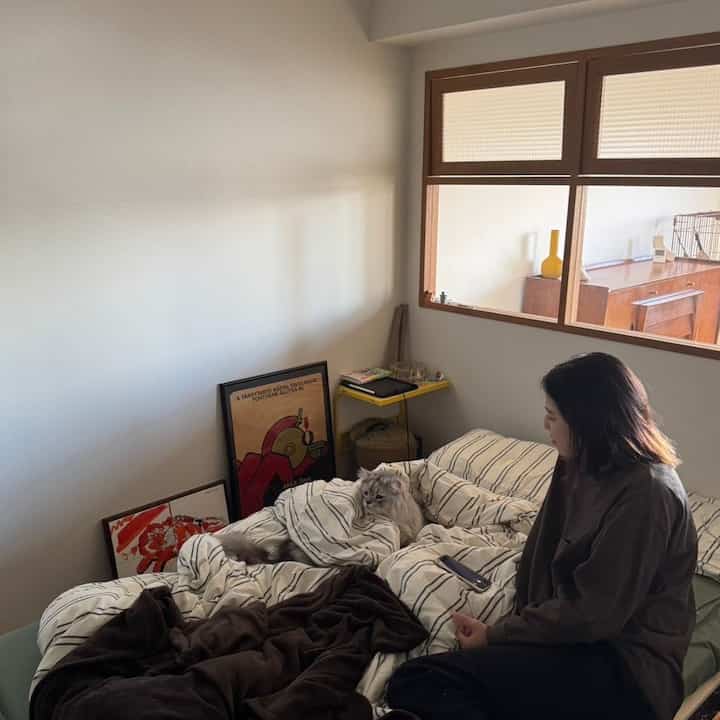 White and natural brown toned bedroom featuring striped duvet cover and a cat creating a cozy atmosphere