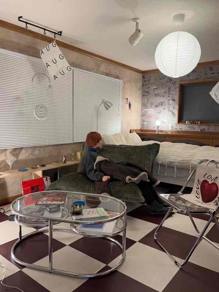 Brown and white toned living-bedroom space featuring mid-century modern sofa and glass coffee table with vintage ambiance