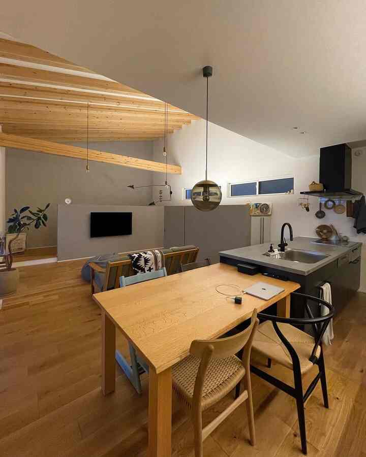 ナチュラルな木目調のダイニングとキッチン、露出した天井梁とペンダントライトが配置されたモダンなインテリア