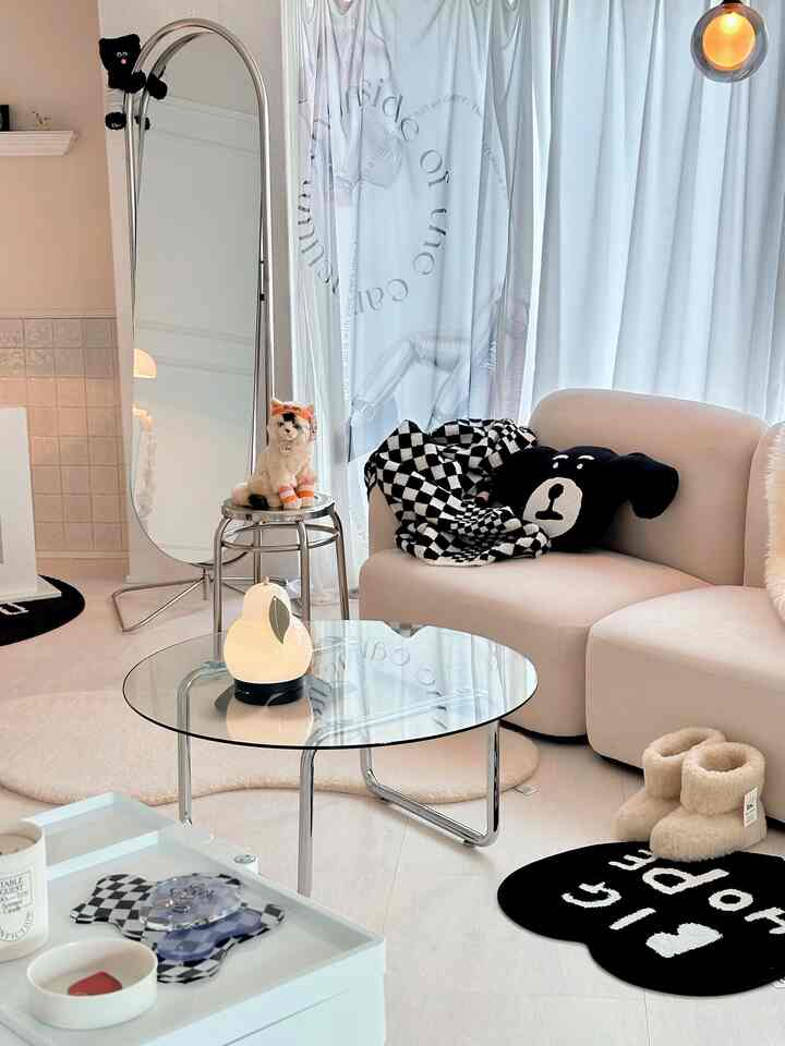 ベージュと白の色調のリビング、ベージュのソファとガラスのテーブル、ペットのぬいぐるみが配置された温かみのある空間