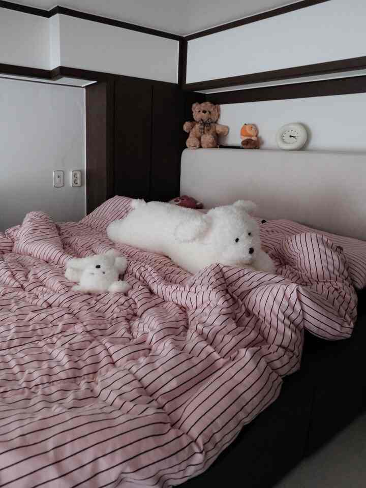 ブラウン調の寝室、ピンクのストライプ寝具と犬型クッションが配置された雰囲気のある空間