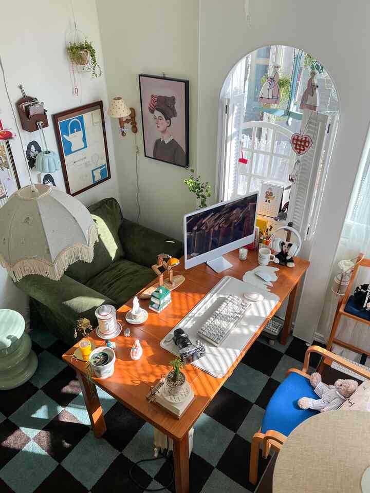 暖かい木目調とミント色のチェックラグがある小さなホームオフィス空間、ヴィンテージ家具とかわいいデスク飾りが配置された居心地の良いインテリア