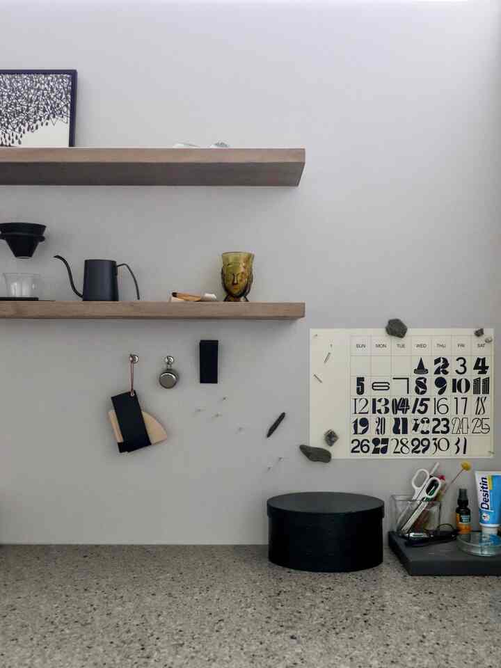白い壁と木製棚のあるキッチンの一角、壁に2025年のカレンダーが掛かり、コーヒー器具が置かれたすっきりとしたおうちカフェの雰囲気