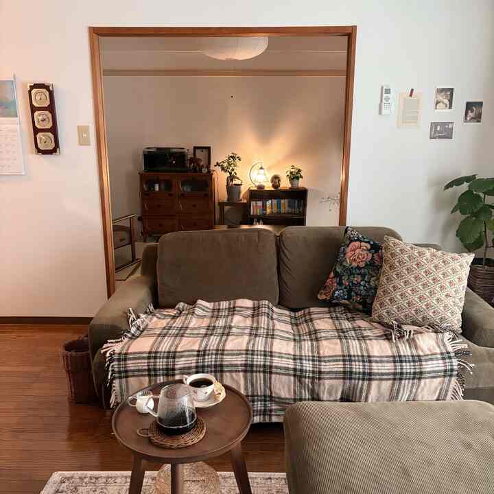 ブラウンとベージュのトーンでまとめられたヴィンテージ風リビング、快適なオリーブグリーンのソファと丸いサイドテーブルが配置された雰囲気のある空間